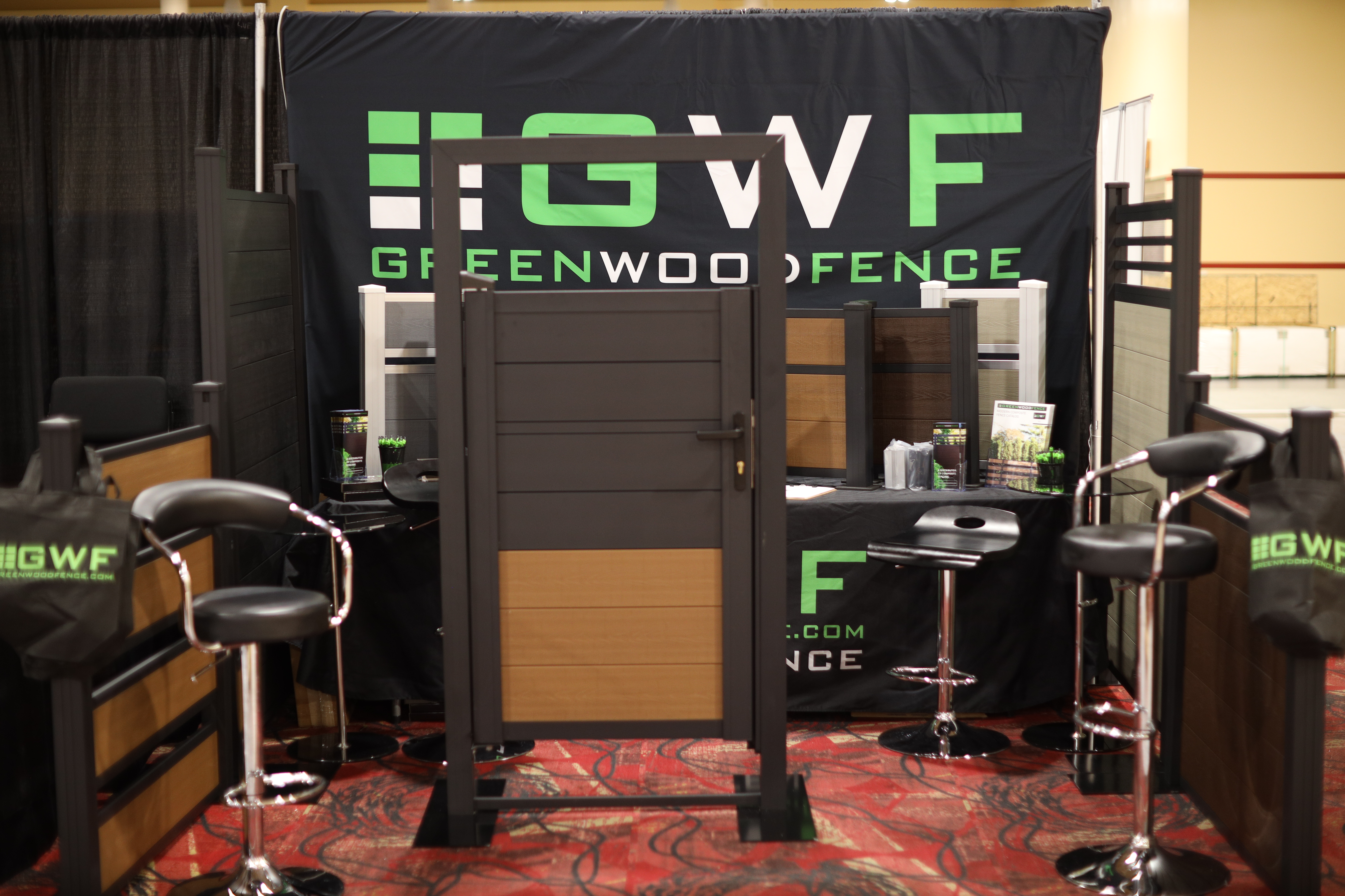 Greenwood Fence trade show booth showcasing modern composite and vinyl fencing with aluminum gates and installation examples.